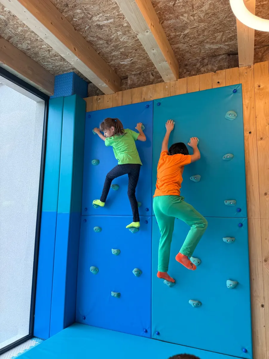 Due bambine salgono sulla parete d'arrampicata azzurra