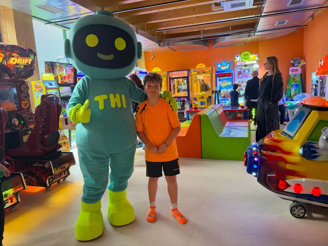 Thi, la mascotte, con un bambino tra i giochi della sala