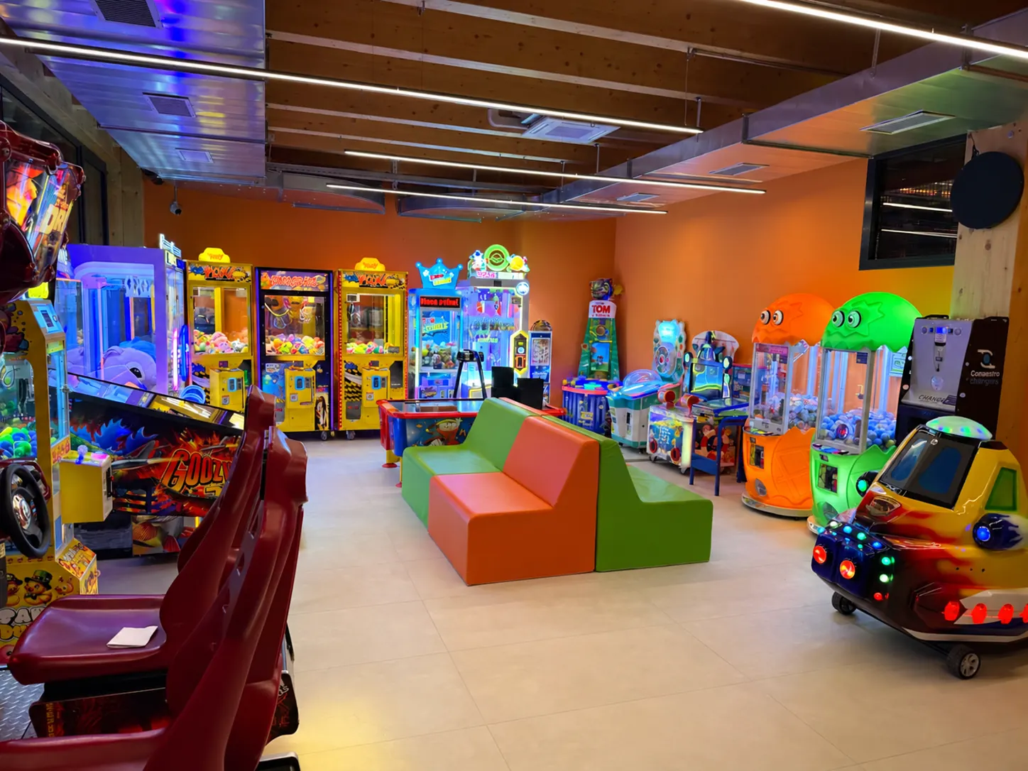 La sala giochi con i videogiochi, le gru dei peluche e i divanetti colorati